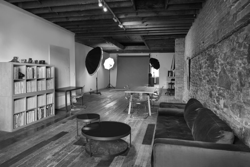 View of Studio with interior stone wall, photo backdrop, bookcase and professional photo lights set up