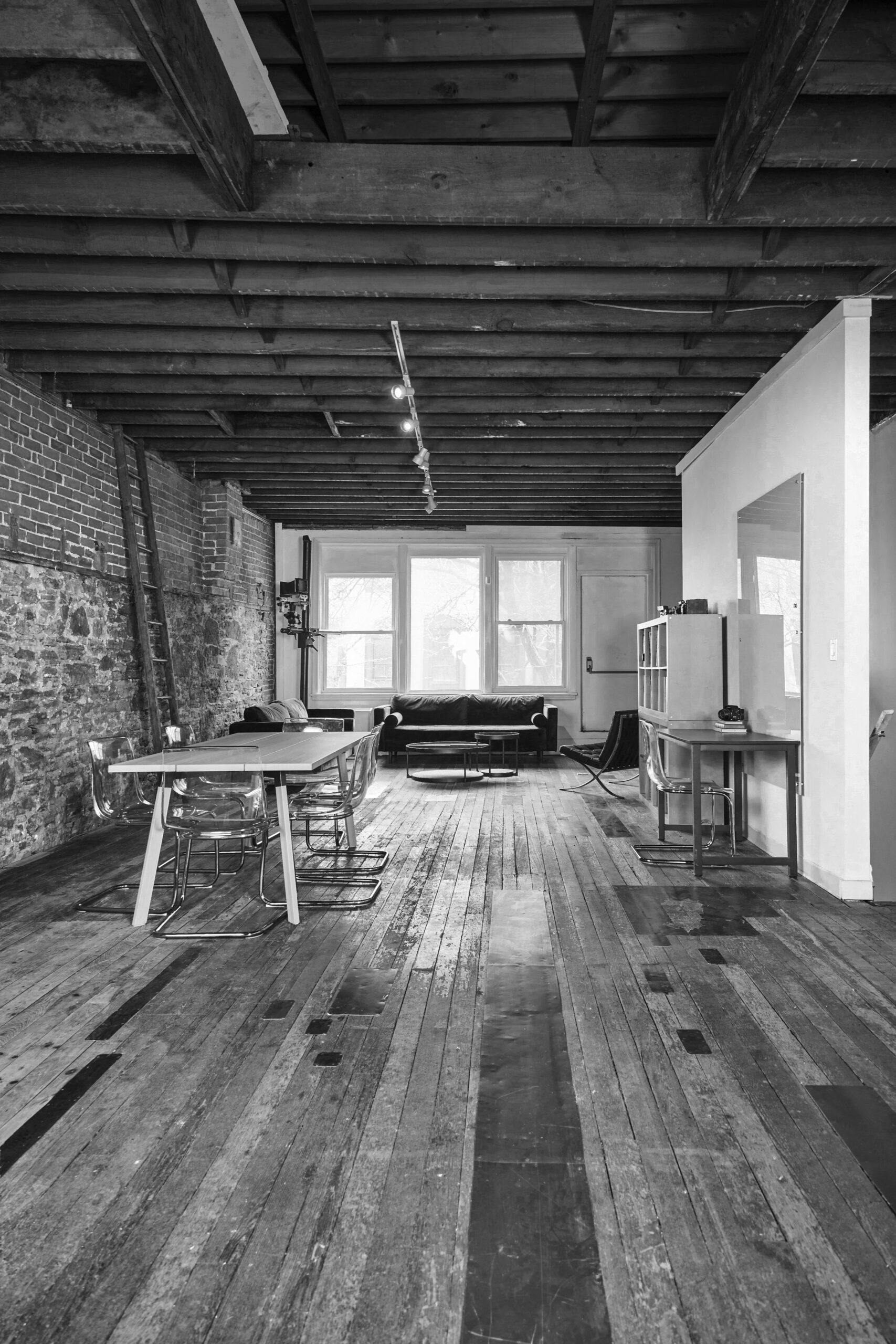 Black and white image of studio room with table and couch against a window