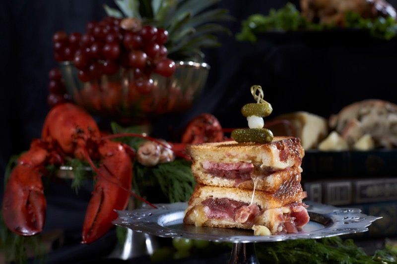 Close up of roast beef sandwich and cheese with food in the background